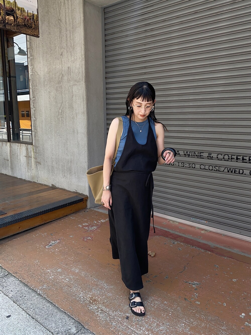 ブラック系のワンピース、ベージュ系のハンドバッグ、ブルー系のタンクトップを着用したレディースの夏コーディネートの3枚目の写真