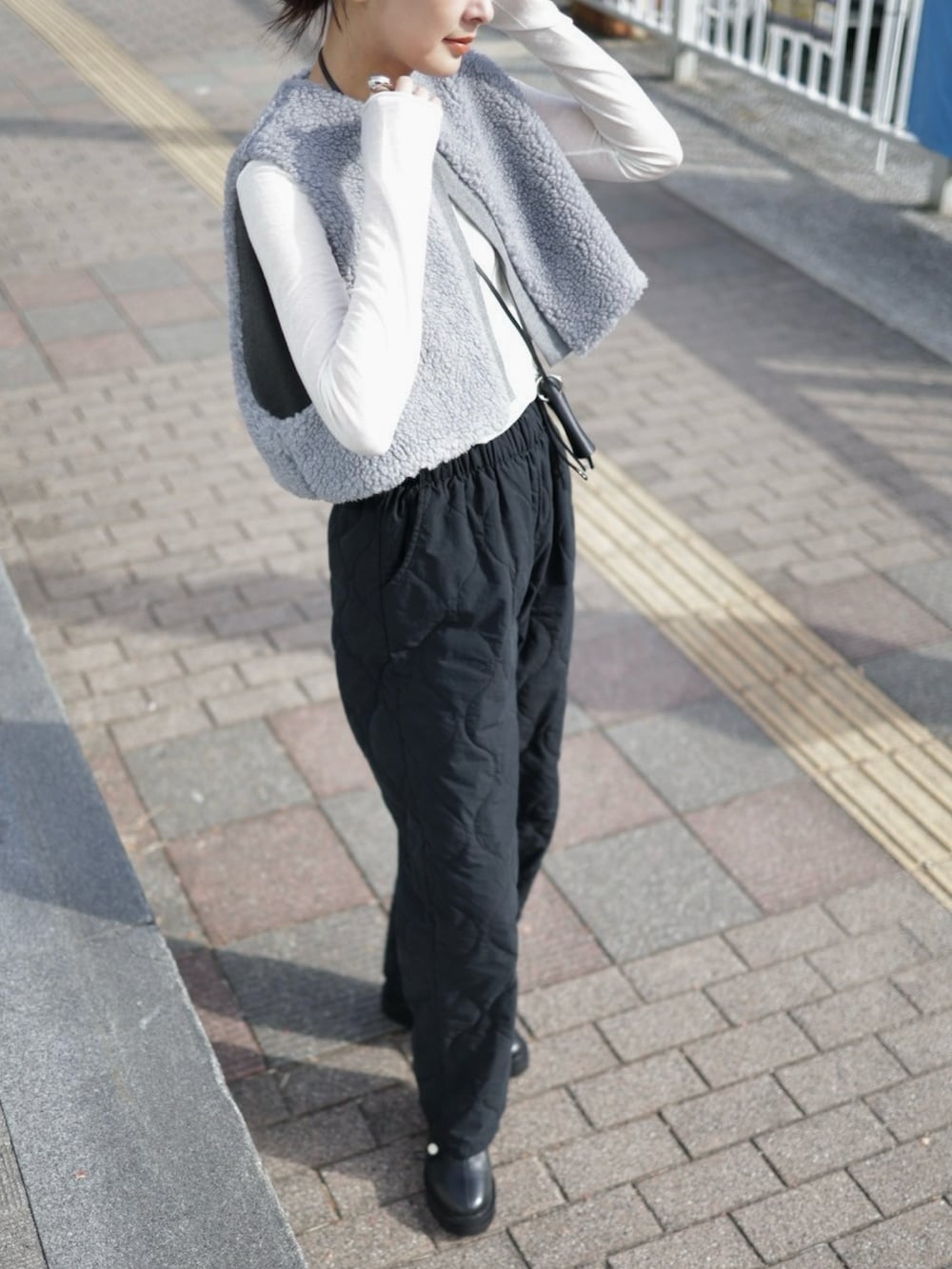 グレー系のベスト、ブラック系のその他パンツ、ブラック系のショルダーバッグを着用したレディースの冬コーディネートの4枚目の写真