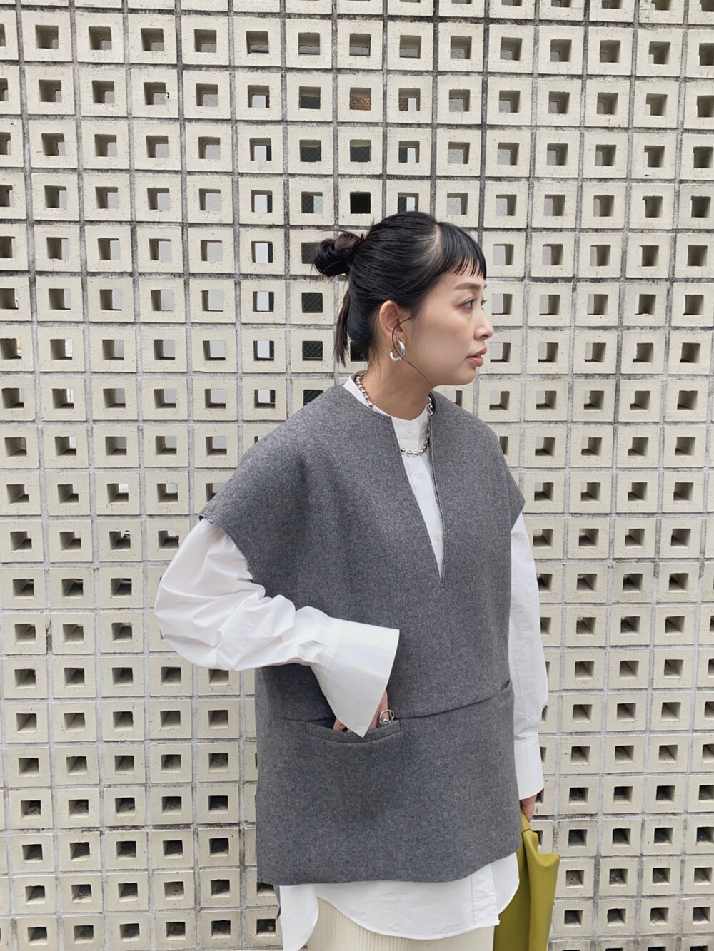 グレー系のベスト、ホワイト系のシャツ/ブラウス、ホワイト系のスカートを着用したレディースの秋コーディネートの2枚目の写真