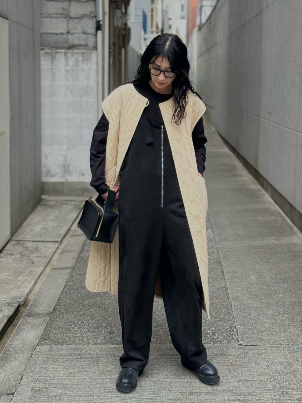 ブラック系のサロペット/オーバーオール、ブラック系のブーツ、ベージュ系のミリタリージャケットを着用したレディースの冬コーディネートの3枚目の写真