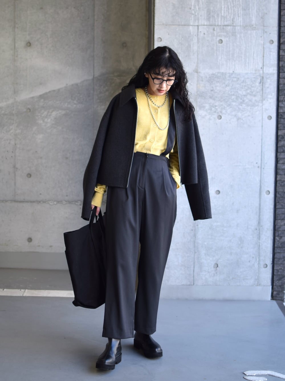 グレー系のブルゾン、イエロー系のカーディガン/ボレロ、グレー系のスラックスを着用したレディースの冬コーディネートの5枚目の写真