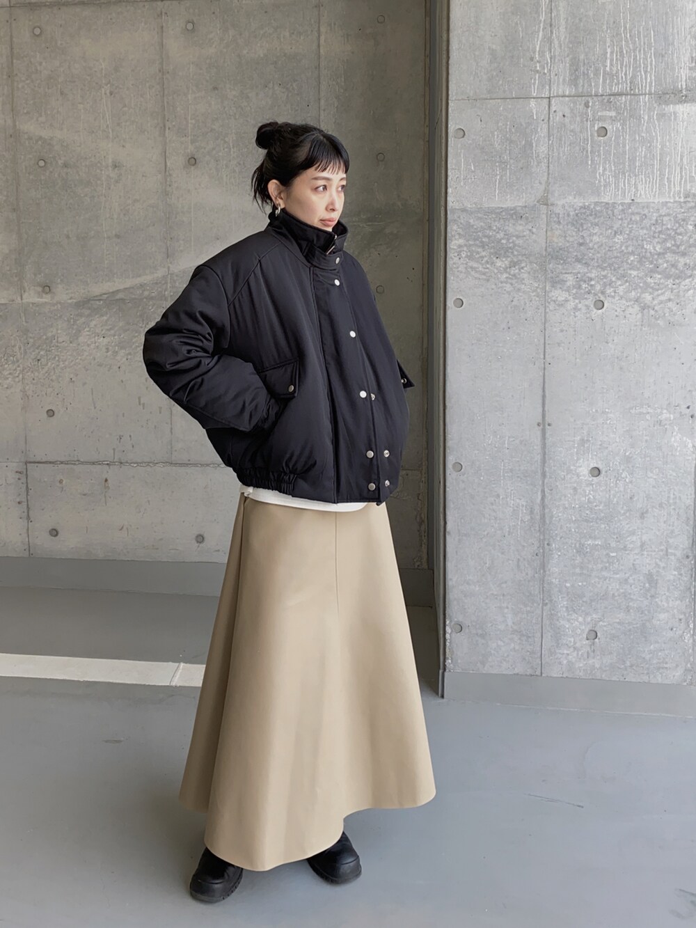 ブラック系のブルゾン、ベージュ系のスカートを着用したレディースの冬コーディネートの2枚目の写真
