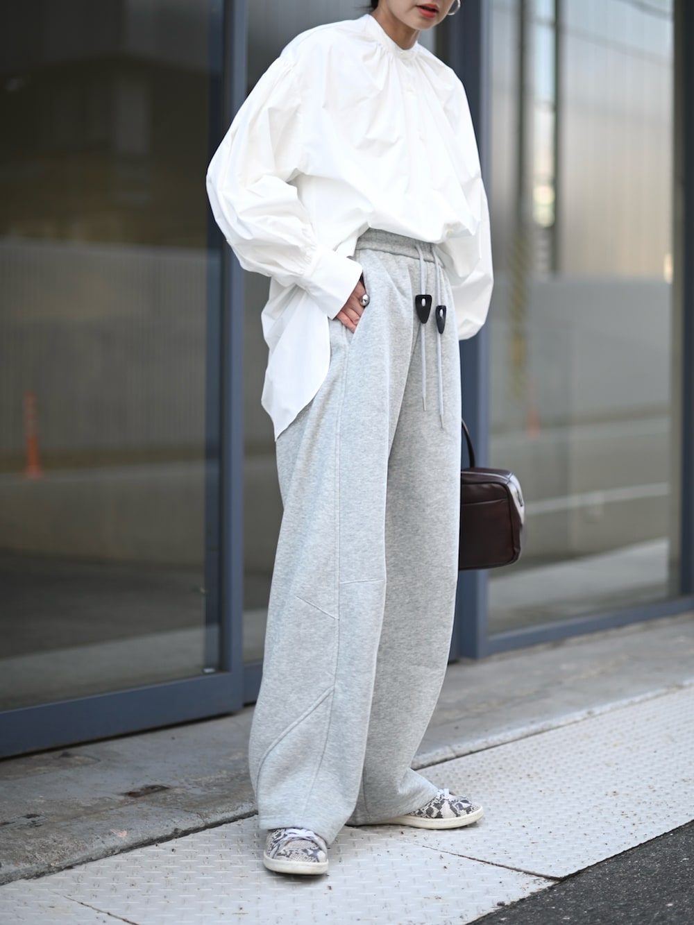 ホワイト系のシャツ/ブラウス、グレー系のスウェットパンツ、その他のスニーカーを着用したレディースの春コーディネートの3枚目の写真