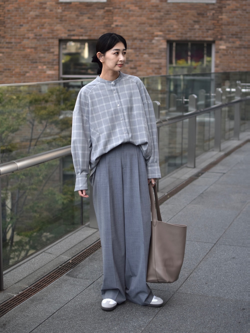 グレー系のシャツ/ブラウス、グレー系のスラックス、ベージュ系のショルダーバッグを着用したレディースの秋コーディネートの4枚目の写真