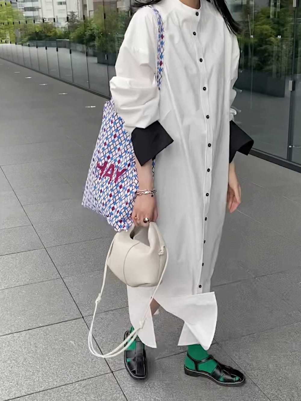 ホワイト系のシャツワンピース、ブラック系のサンダル、ブラック系のハットを着用したレディースの春コーディネートの3枚目の写真