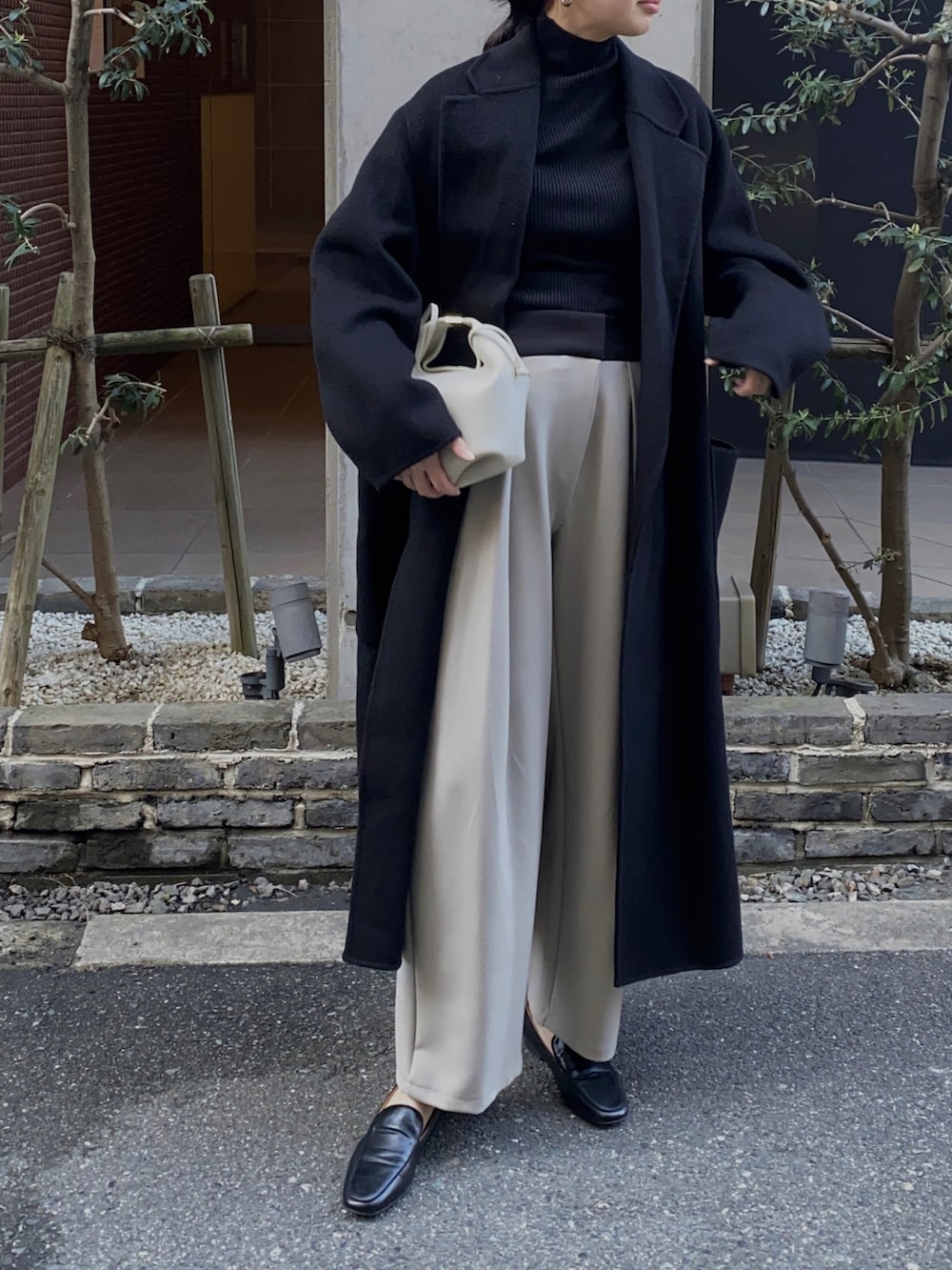 ブラック系のチェスターコート、ブラック系のローファーを着用したレディースの冬コーディネートの2枚目の写真