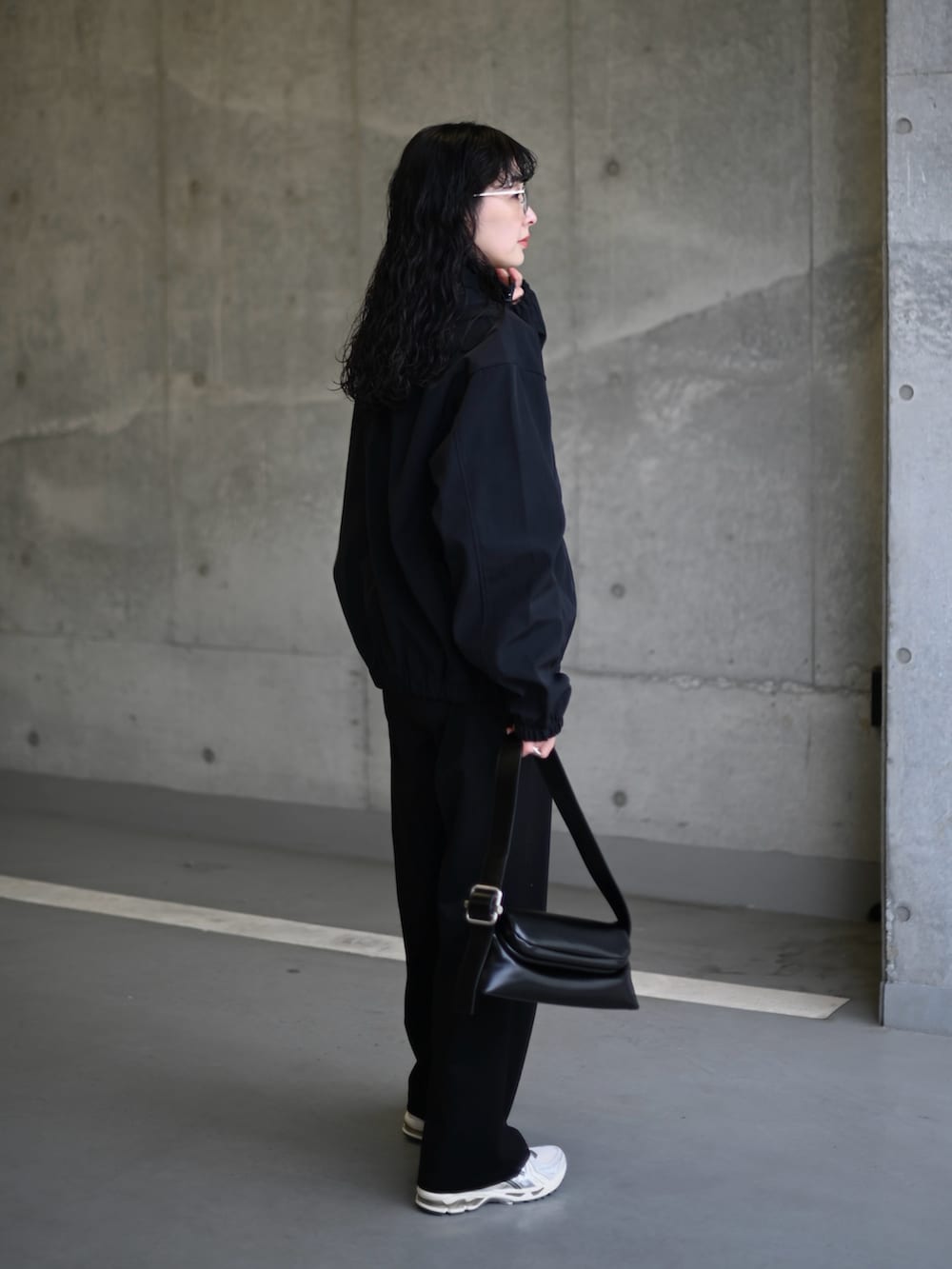 ブラック系のナイロンジャケット、シルバー系のスニーカー、ブラック系のショルダーバッグを着用したレディースの春コーディネートの2枚目の写真