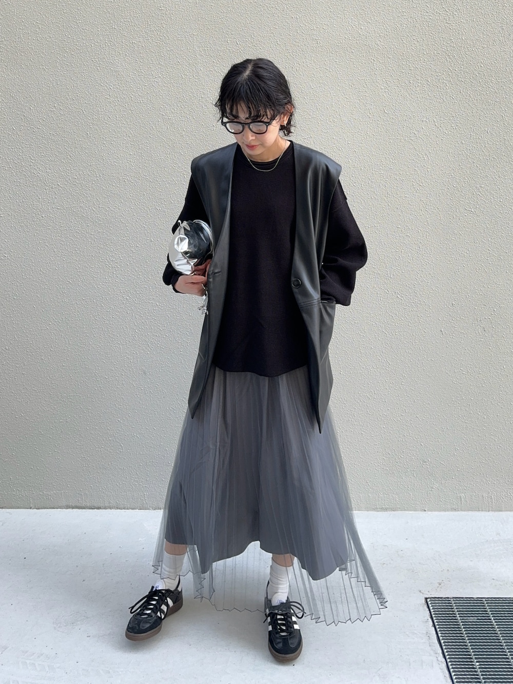ブラック系のスカート、シルバー系のショルダーバッグ、ブラック系のスニーカーを着用したレディースの春コーディネートの2枚目の写真