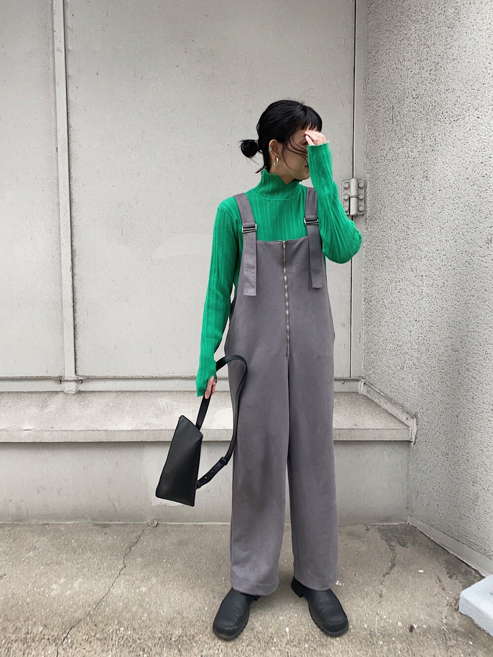 グレー系のサロペット/オーバーオール、グリーン系のニット/セーター、ブラック系のショルダーバッグを着用したレディースの冬コーディネートの3枚目の写真