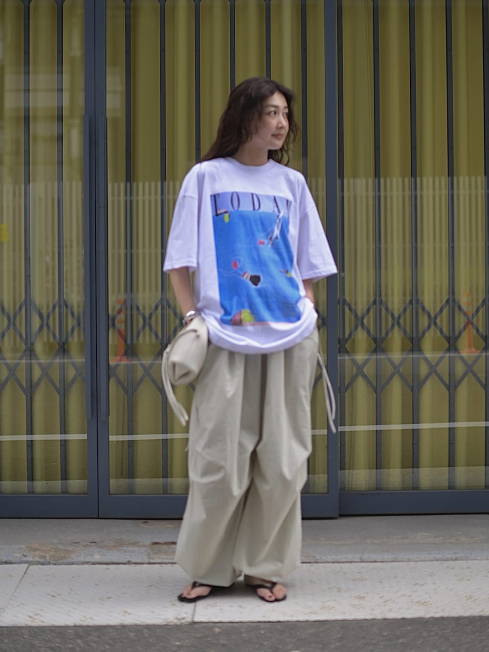 ホワイト系のTシャツ/カットソー、ホワイト系のショルダーバッグ、グレー系のパンツを着用したレディースの夏コーディネートの5枚目の写真