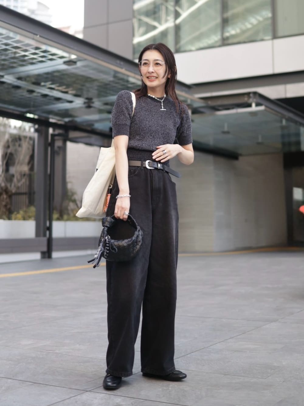 ブラック系のローファー、ブラック系のニット/セーター、ブラック系のデニムパンツを着用したレディースの春コーディネートの2枚目の写真