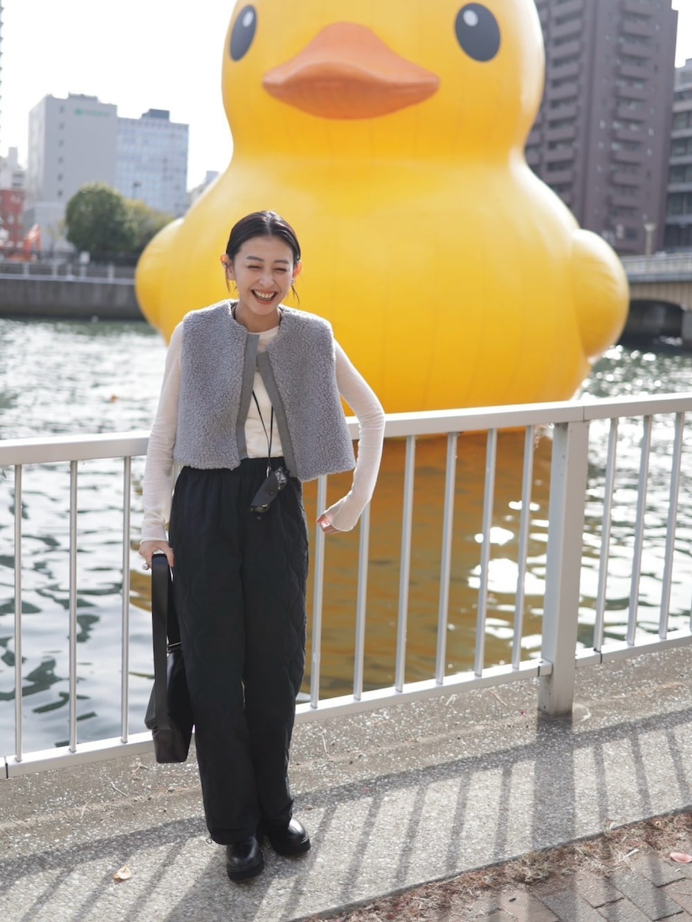 グレー系のベスト、ブラック系のその他パンツ、ブラック系のショルダーバッグを着用したレディースの冬コーディネートの2枚目の写真