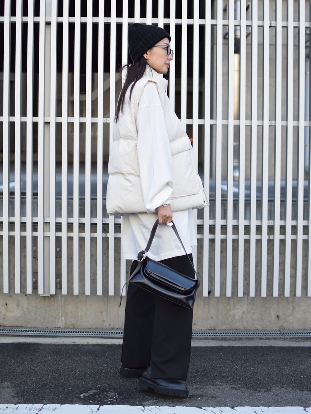 ホワイト系のダウンベスト、ブラック系のその他パンツ、ブラック系のショルダーバッグを着用したレディースの冬コーディネートの2枚目の写真