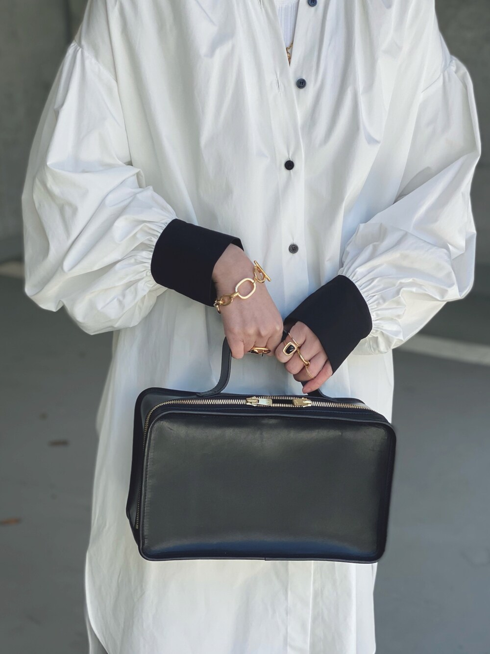 ホワイト系のシャツワンピース、ブラック系のハンドバッグ、ゴールド系のネックレスを着用したレディースの冬コーディネートの3枚目の写真