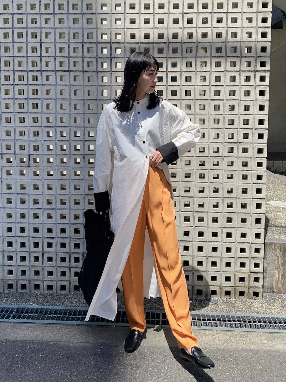 ブラック系のシャツワンピース、ブラック系のトートバッグ、オレンジ系のその他パンツを着用したレディースの春コーディネートの2枚目の写真