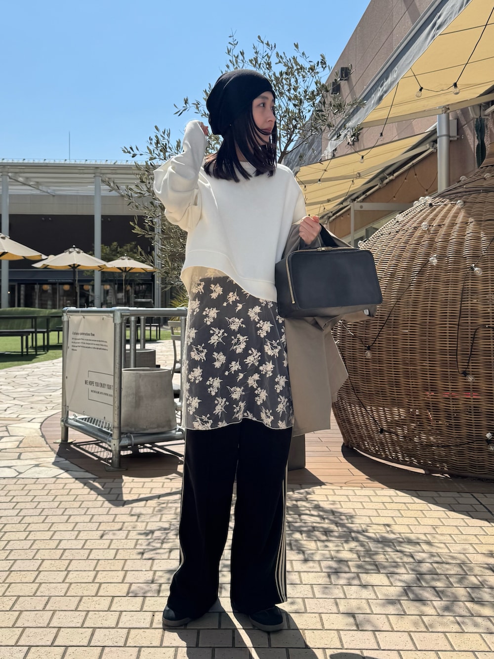 ブラック系のスウェットパンツ、ベージュ系のステンカラーコート、ブラック系のニットキャップ/ビーニーを着用したレディースの春コーディネートの2枚目の写真