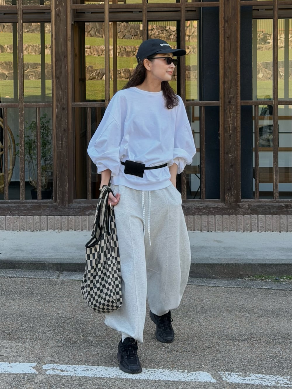 ホワイト系のTシャツ/カットソー、グレー系のスウェットパンツ、ブラック系のトートバッグを着用したレディースの秋コーディネートの2枚目の写真