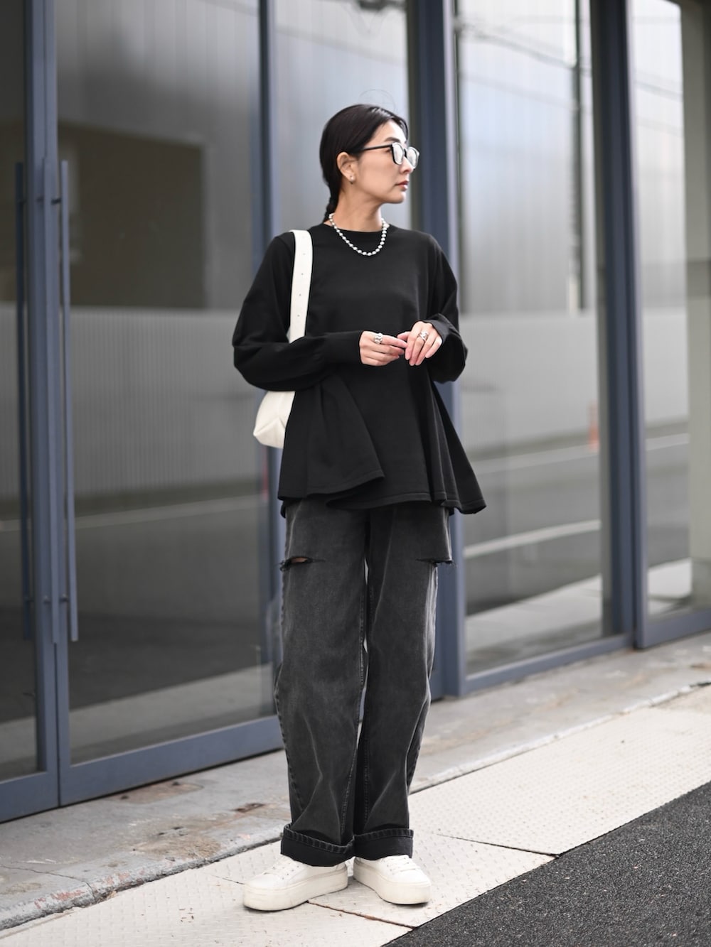 ブラック系のニット/セーター、ブラック系のデニムパンツ、ホワイト系のショルダーバッグを着用したレディースの秋コーディネートの5枚目の写真