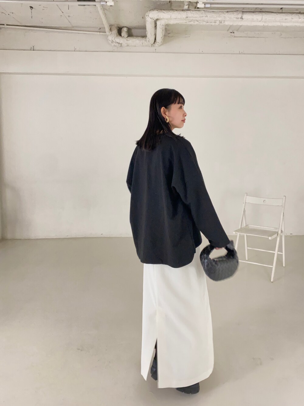 ホワイト系のスカート、ブラック系のブーツ、シルバー系のネックレスを着用したレディースの春コーディネートの2枚目の写真