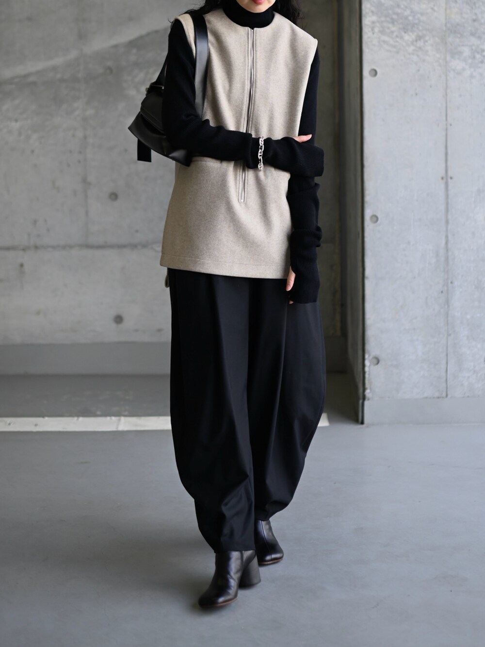 ベージュ系のベスト、ブラック系のスラックス、ブラック系のブーツを着用したレディースの冬コーディネートの3枚目の写真