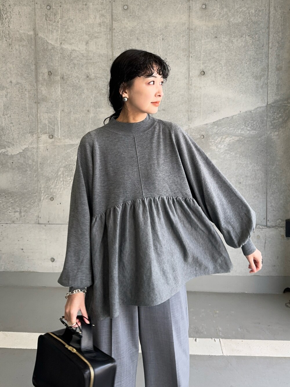 グレー系のニット/セーター、グレー系のスラックス、グレー系のスニーカーを着用したレディースの冬コーディネートの3枚目の写真