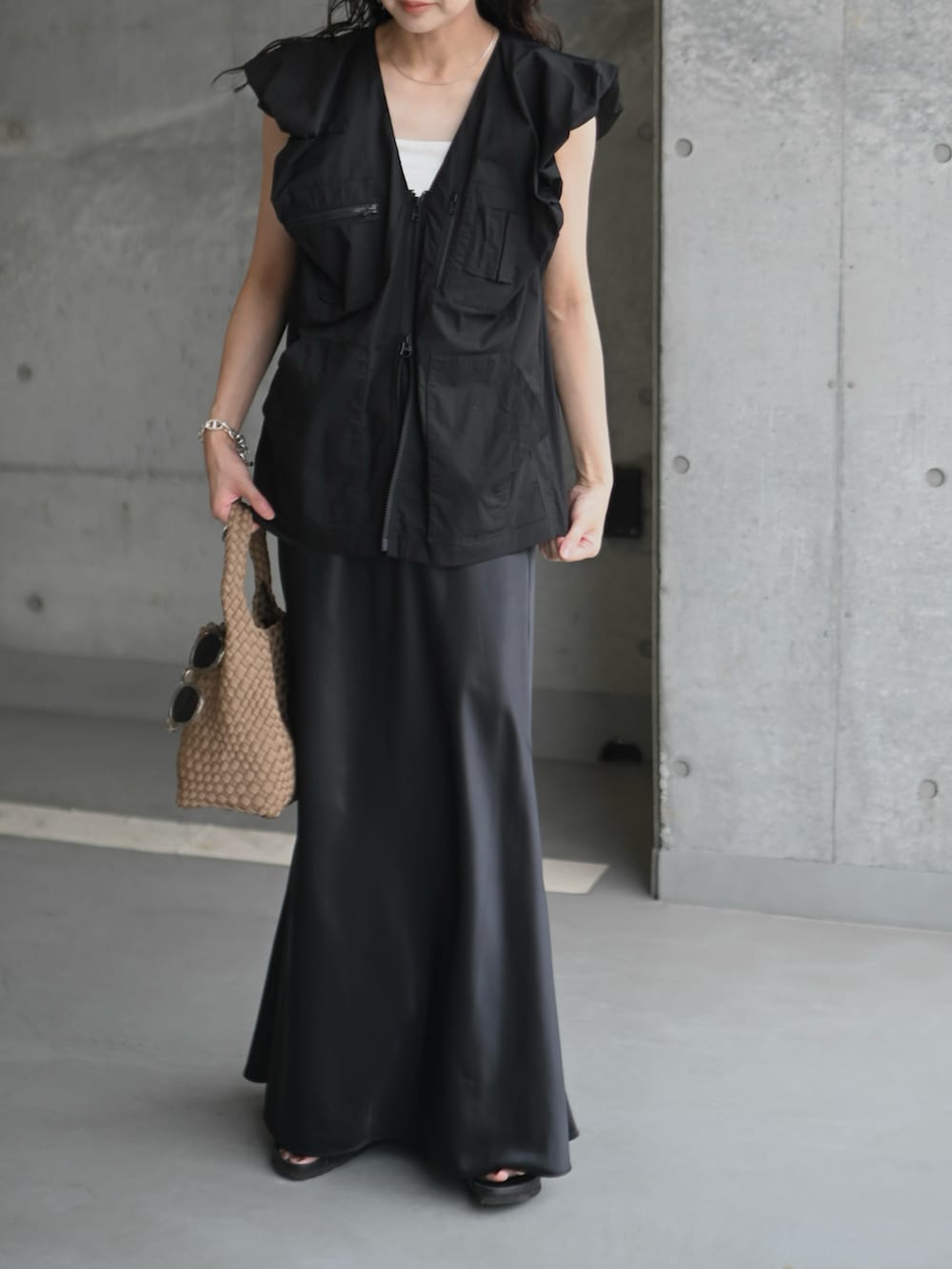 ブラック系のベスト、ブラック系のサンダル、ブラック系のスカートを着用したレディースの夏コーディネートの4枚目の写真