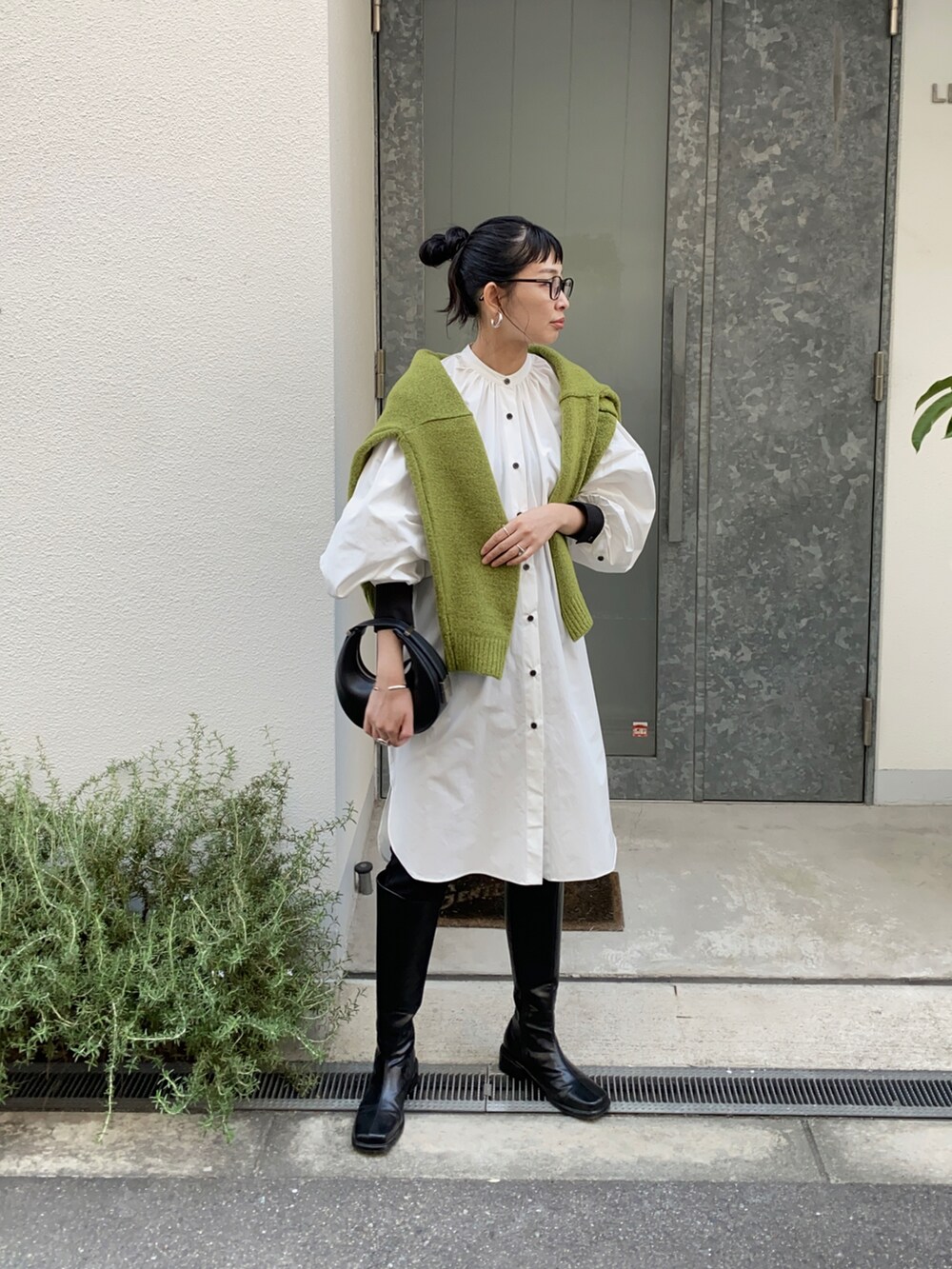 グリーン系のニット/セーター、ホワイト系のシャツワンピース、ブラック系のハンドバッグを着用したレディースの秋コーディネートの3枚目の写真
