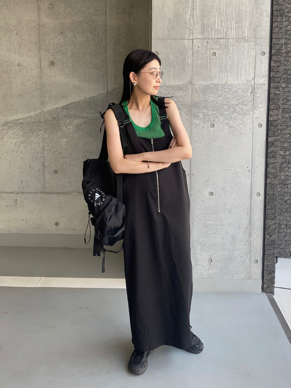 ブラック系のジャンパースカート、グリーン系のニット/セーター、ブラック系のバックパック/リュックを着用したレディースの夏コーディネートの3枚目の写真