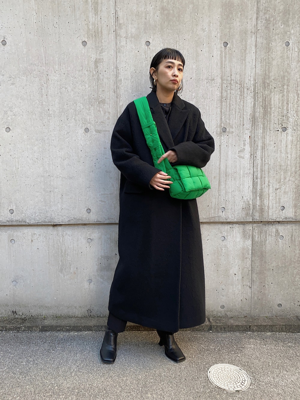 ブラック系のチェスターコート、ブラック系のブーツ、ゴールド系のバレッタ/ヘアクリップを着用したレディースの冬コーディネートの2枚目の写真