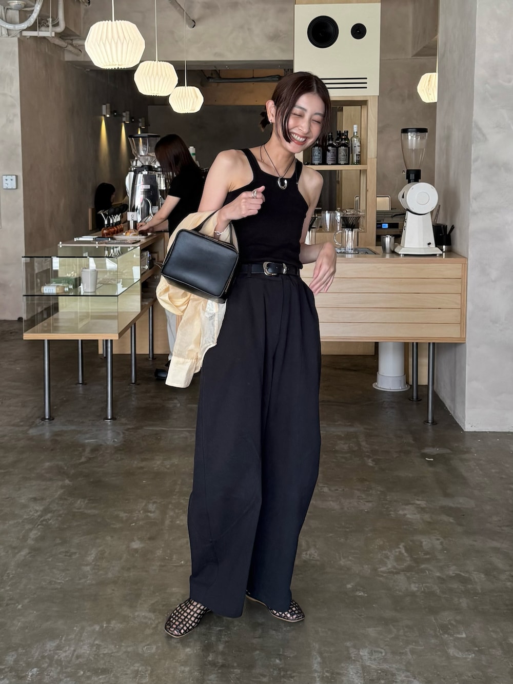 ブラック系のタンクトップ、ブラウン系のバレエシューズ、ブラック系のチノパンツを着用したレディースの秋コーディネートの4枚目の写真