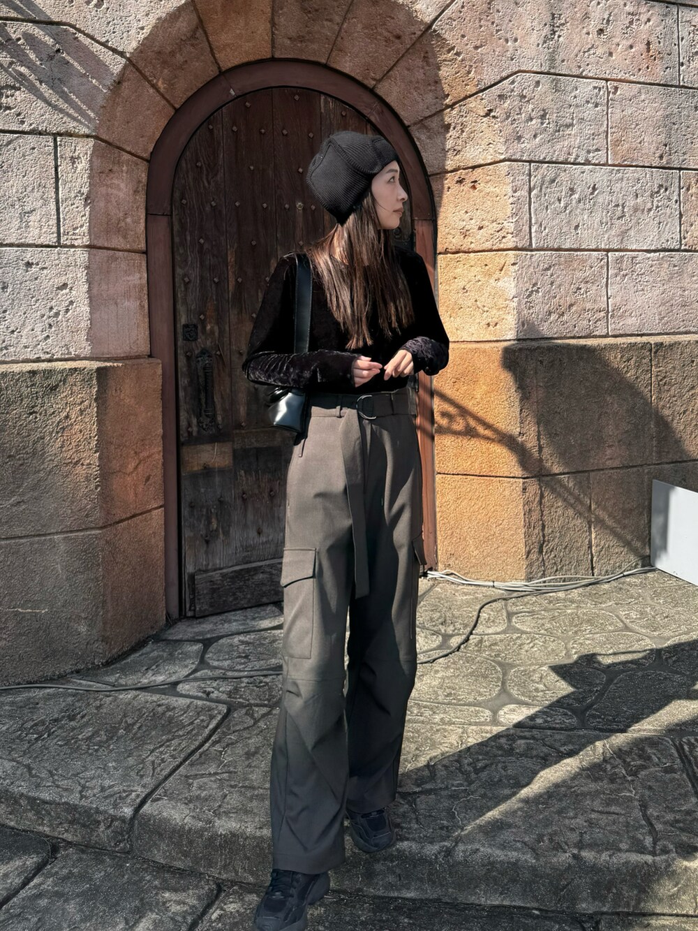 グレー系のパンツ、ブラック系のスニーカー、ブラック系のショルダーバッグを着用したレディースの秋コーディネートの3枚目の写真