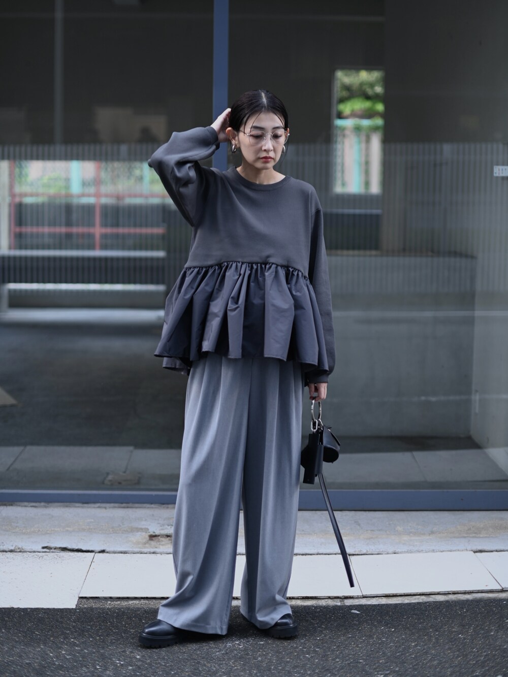 グレー系のニット/セーター、ブラック系のショルダーバッグ、グレー系のスラックスを着用したレディースの秋コーディネートの2枚目の写真