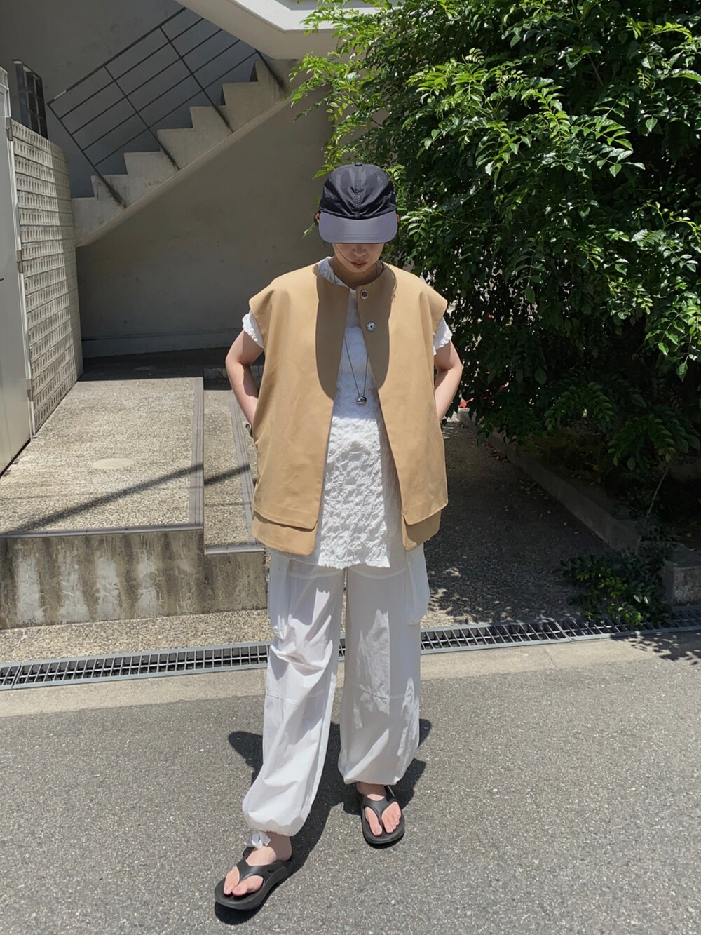 ベージュ系のベスト、ブラック系のサンダル、ブラック系のキャップを着用したレディースの秋コーディネートの4枚目の写真