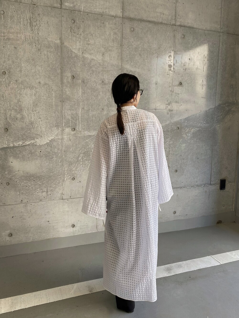 ホワイト系のワンピース、ベージュ系のハンドバッグ、ブラック系のサンダルを着用したレディースの夏コーディネートの3枚目の写真