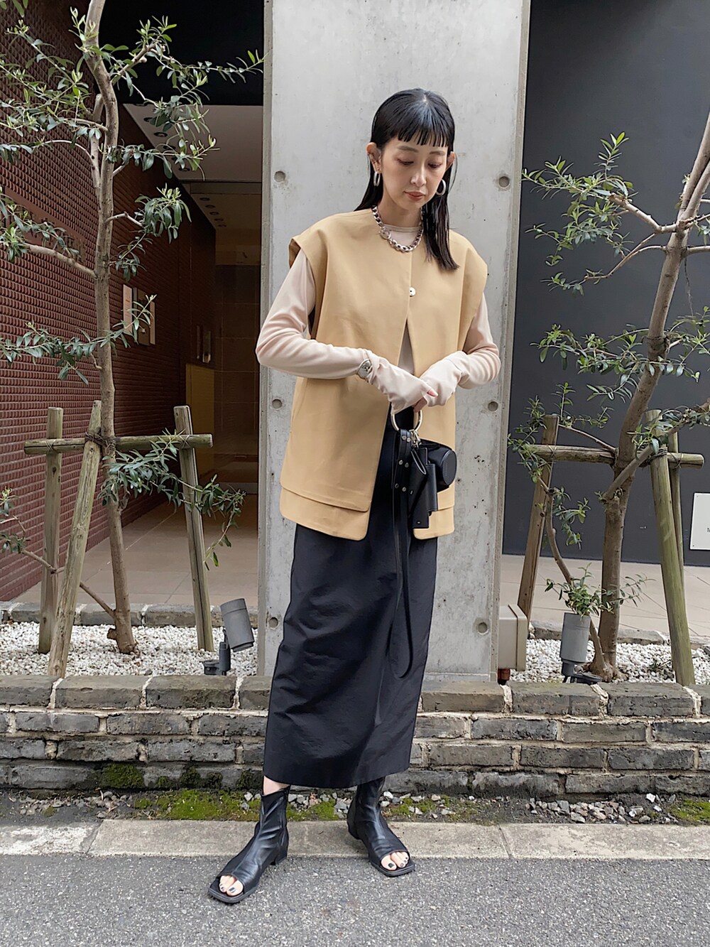 ベージュ系のTシャツ/カットソー、ブラック系のショルダーバッグ、ベージュ系のベストを着用したレディースの春コーディネートの2枚目の写真