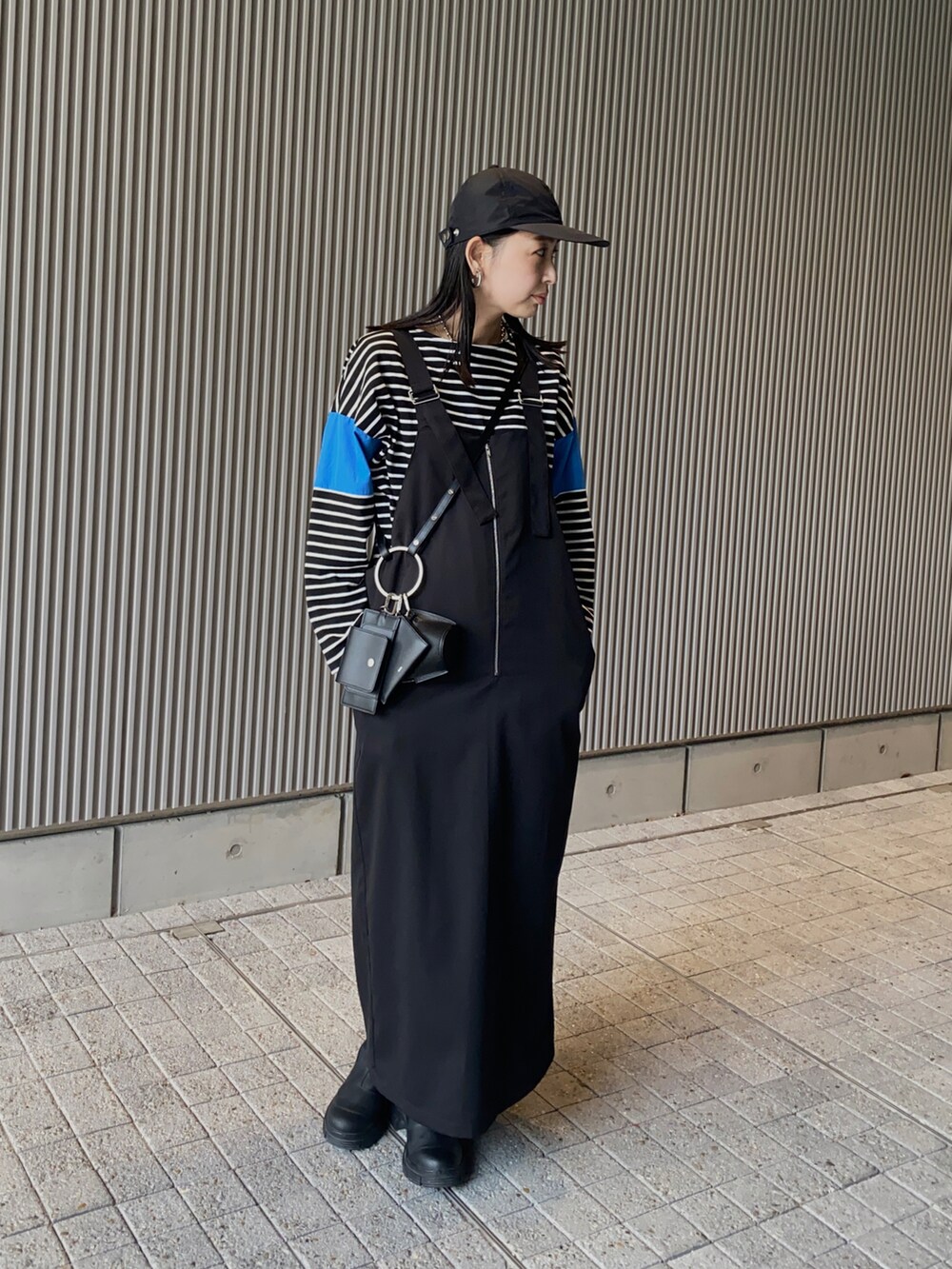 ブルー系のTシャツ/カットソー、ブラック系のジャンパースカート、ブラック系のショルダーバッグを着用したレディースの春コーディネートの3枚目の写真