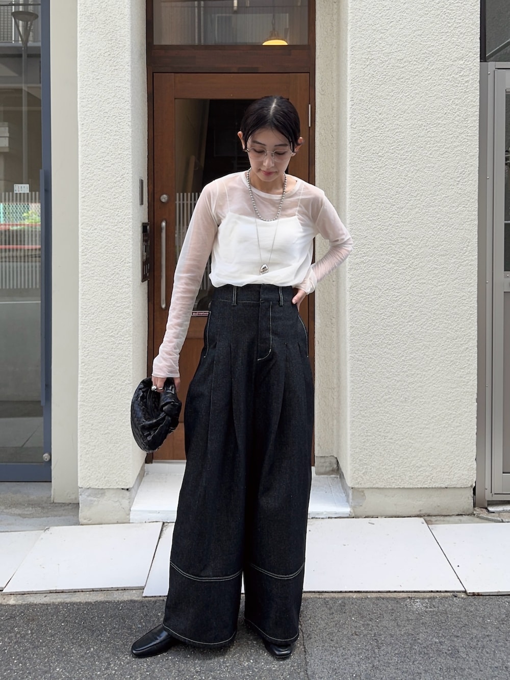 ブラック系のデニムパンツ、ホワイト系のキャミソール、ホワイト系のTシャツ/カットソーを着用したレディースの秋コーディネートの2枚目の写真