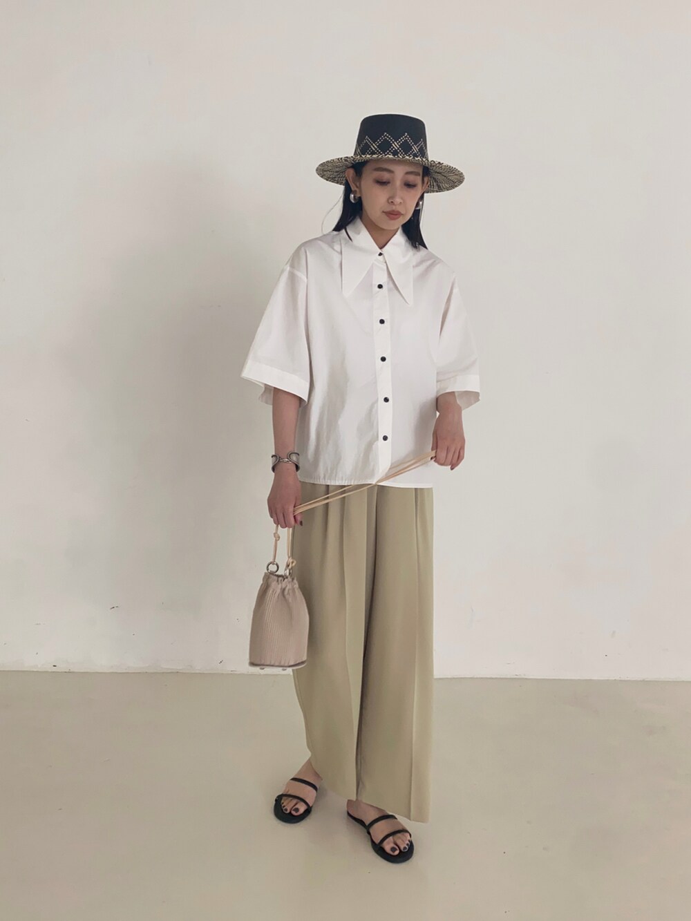 ホワイト系のシャツ/ブラウス、ブラック系のサンダル、ブラック系のハットを着用したレディースの夏コーディネートの2枚目の写真