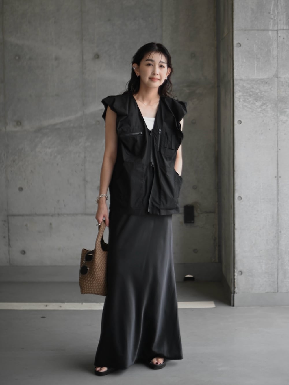 ブラック系のベスト、ブラック系のサンダル、ブラック系のスカートを着用したレディースの夏コーディネートの2枚目の写真