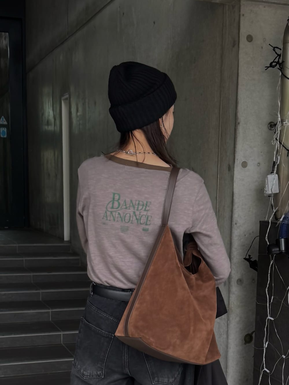 グレー系のTシャツ/カットソー、ブラック系のデニムパンツ、ブラウン系のショルダーバッグを着用したレディースの秋コーディネートの2枚目の写真