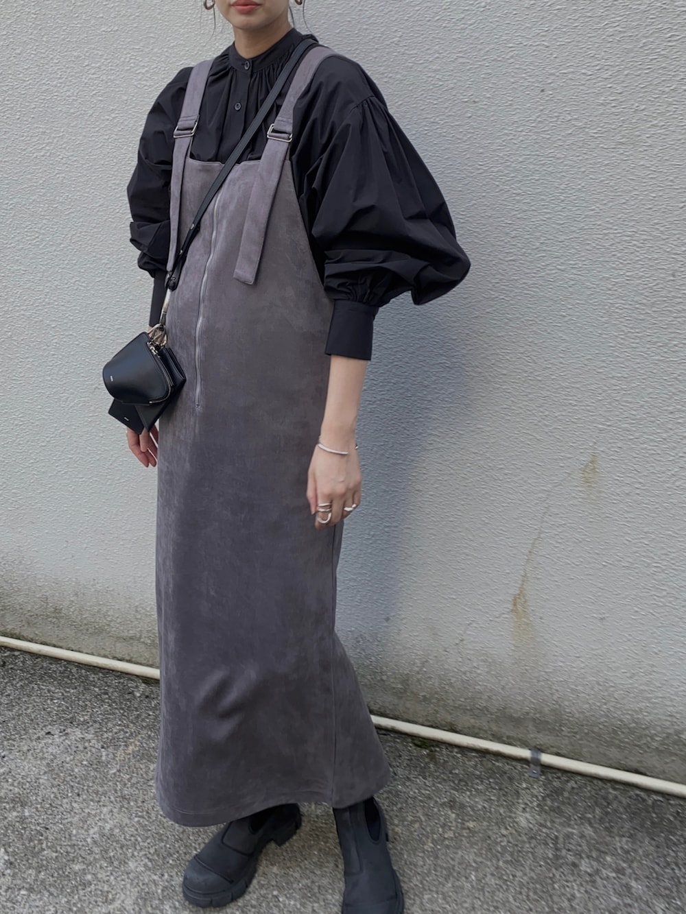 グレー系のジャンパースカート、ブラック系のシャツ/ブラウス、ブラック系のブーツを着用したレディースの冬コーディネートの2枚目の写真