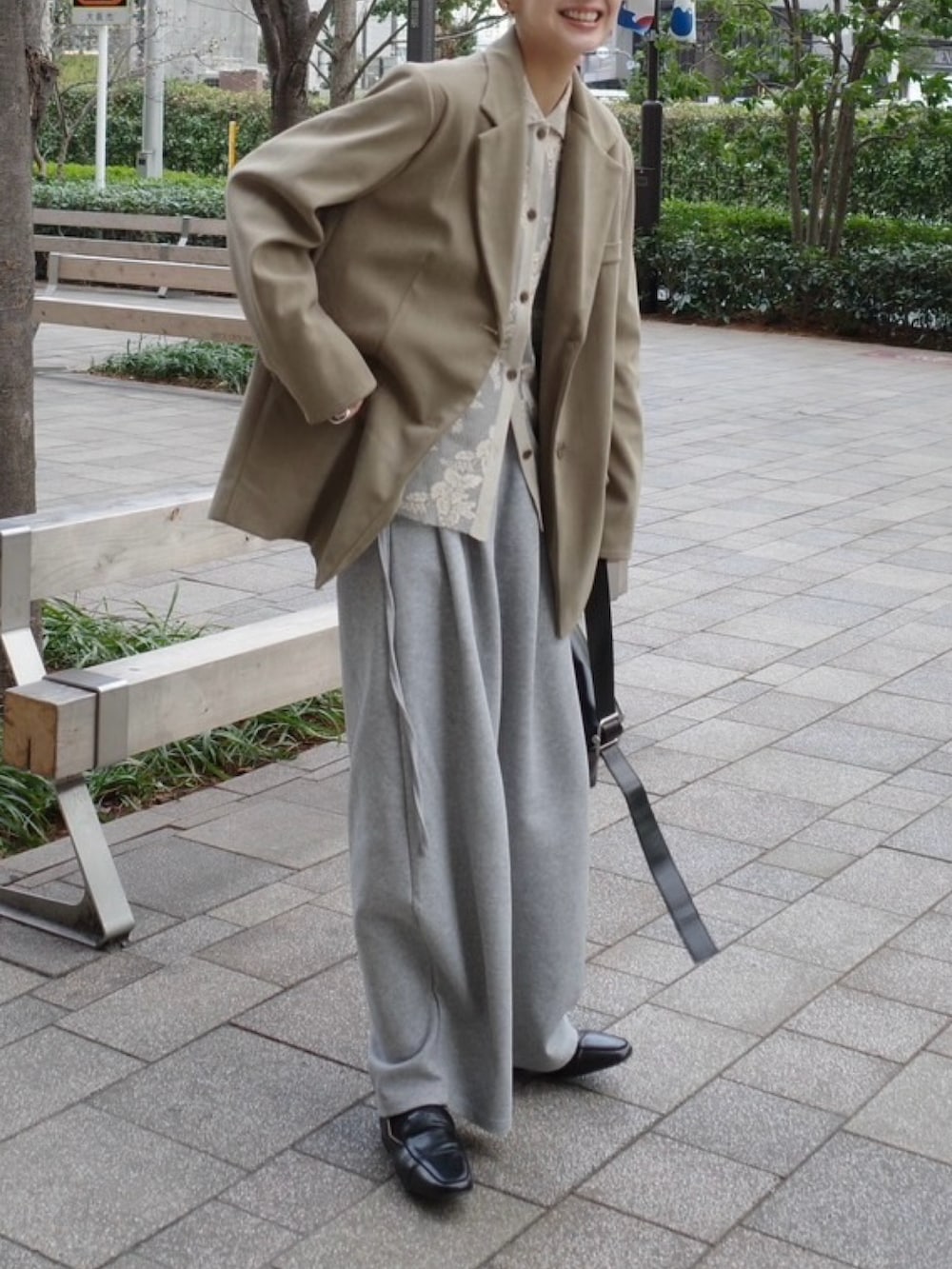 ベージュ系のテーラードジャケット、ブラック系のショルダーバッグ、グレー系のスウェットパンツを着用したレディースの春コーディネートの3枚目の写真