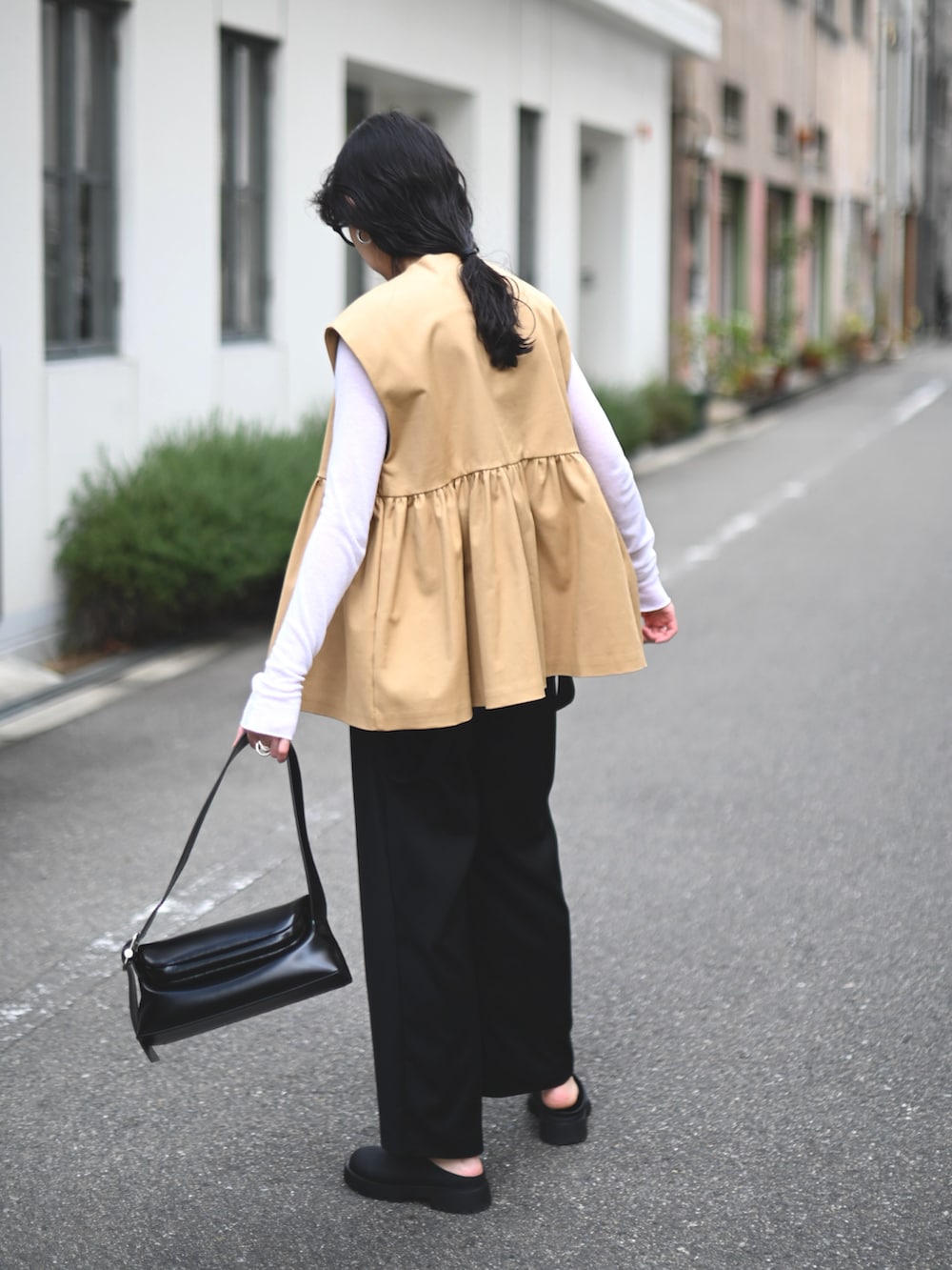 ベージュ系のベスト、ブラック系のショルダーバッグ、ブラック系のスラックスを着用したレディースの春コーディネートの4枚目の写真