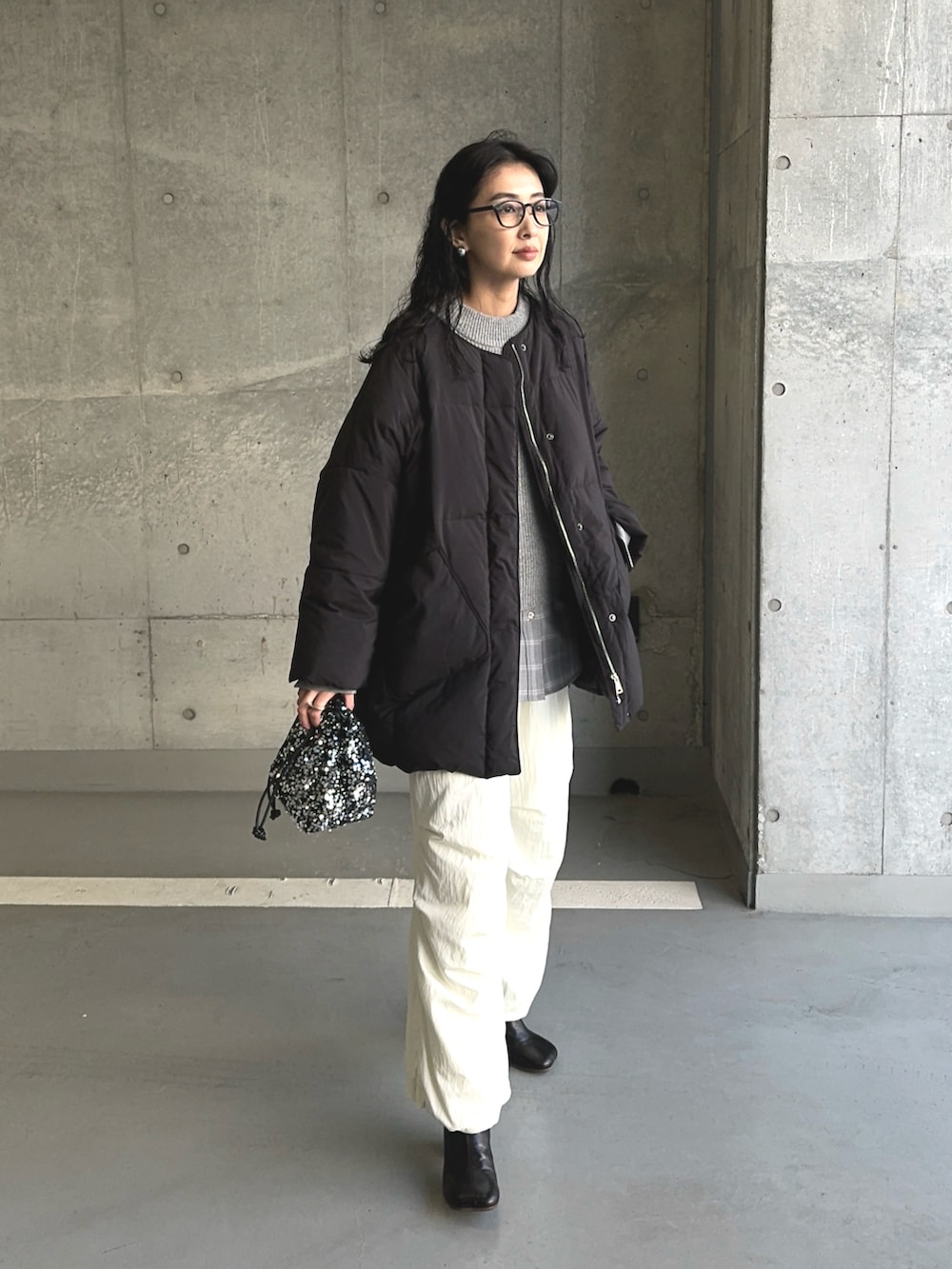 ブラック系のダウンジャケット/コート、シルバー系のショルダーバッグ、ホワイト系のその他パンツを着用したレディースの冬コーディネートの4枚目の写真