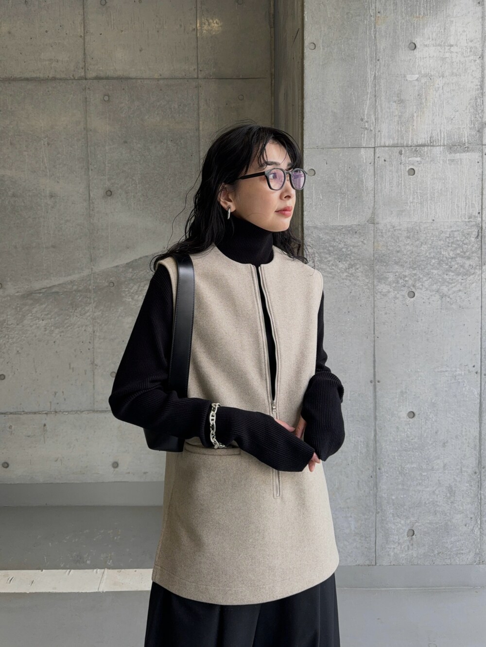 ベージュ系のベスト、ブラック系のスラックス、ブラック系のブーツを着用したレディースの冬コーディネートの4枚目の写真