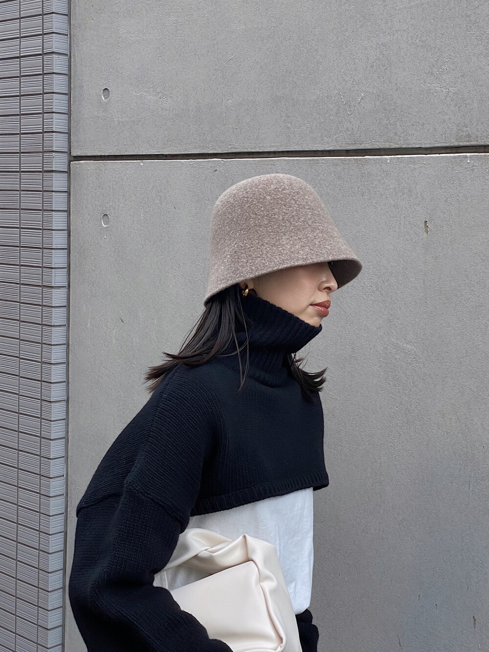 ブラック系のニット/セーター、ブラック系のスカート、ホワイト系のTシャツ/カットソーを着用したレディースの冬コーディネートの2枚目の写真