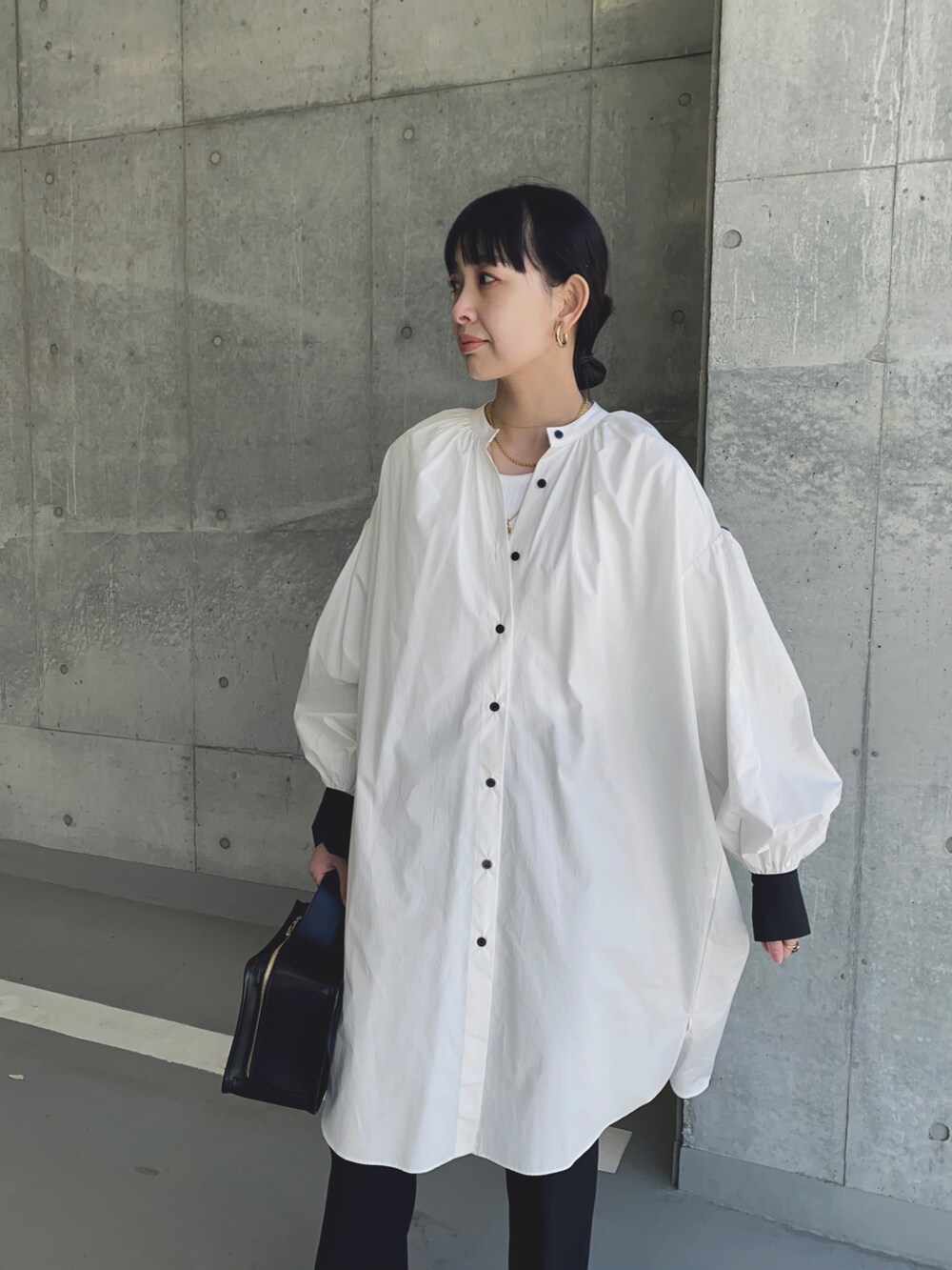 ホワイト系のシャツワンピース、ブラック系のハンドバッグ、ゴールド系のネックレスを着用したレディースの冬コーディネートの2枚目の写真