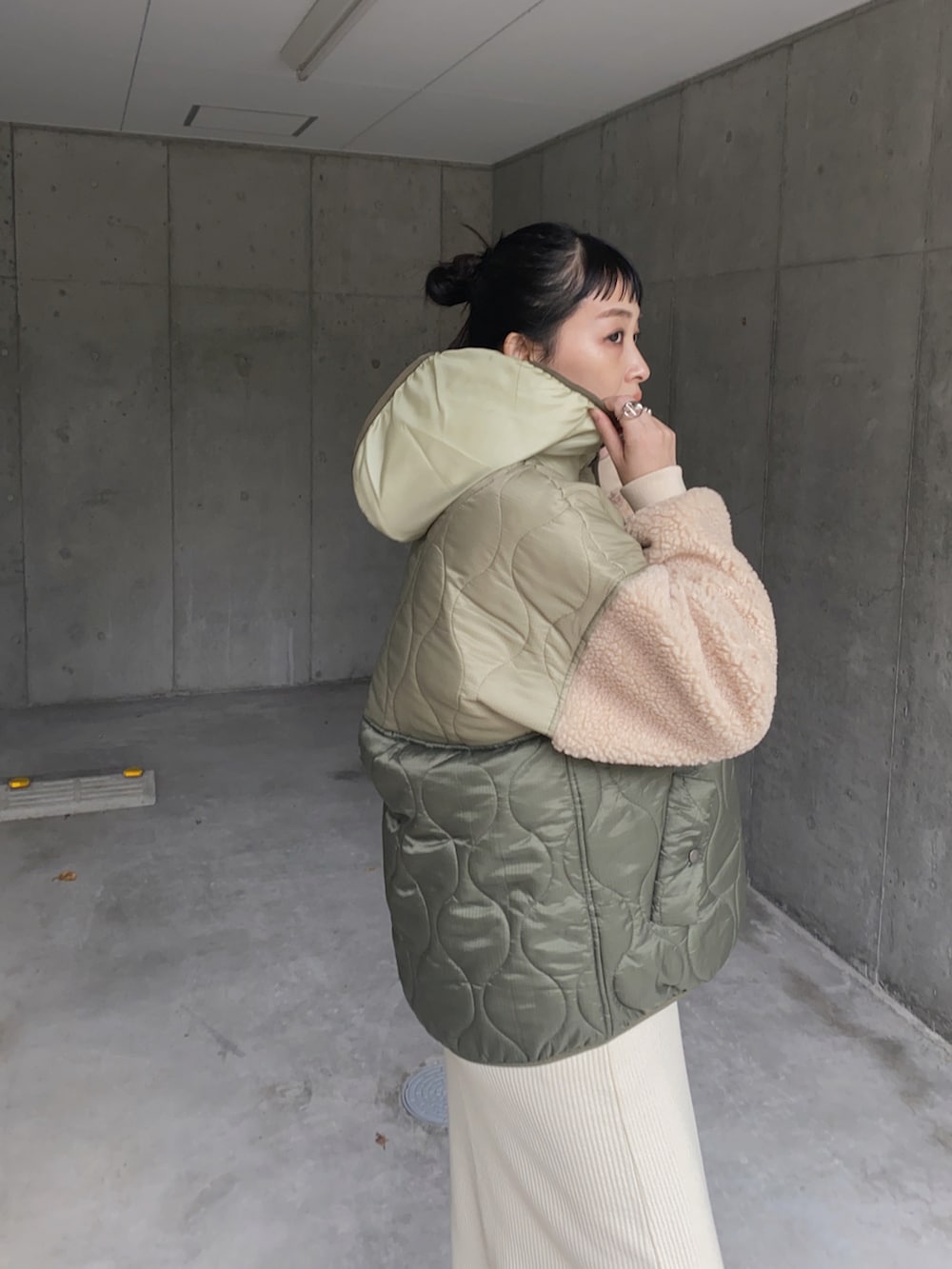 グリーン系のダウンジャケット/コート、ホワイト系のスカート、ブラック系のブーツを着用したレディースの秋コーディネートの3枚目の写真