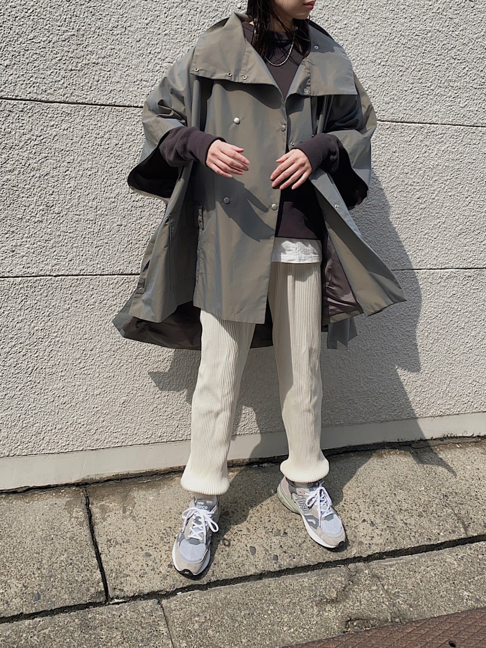グリーン系のポンチョ、ホワイト系のその他パンツ、グレー系のスニーカーを着用したレディースの春コーディネートの2枚目の写真