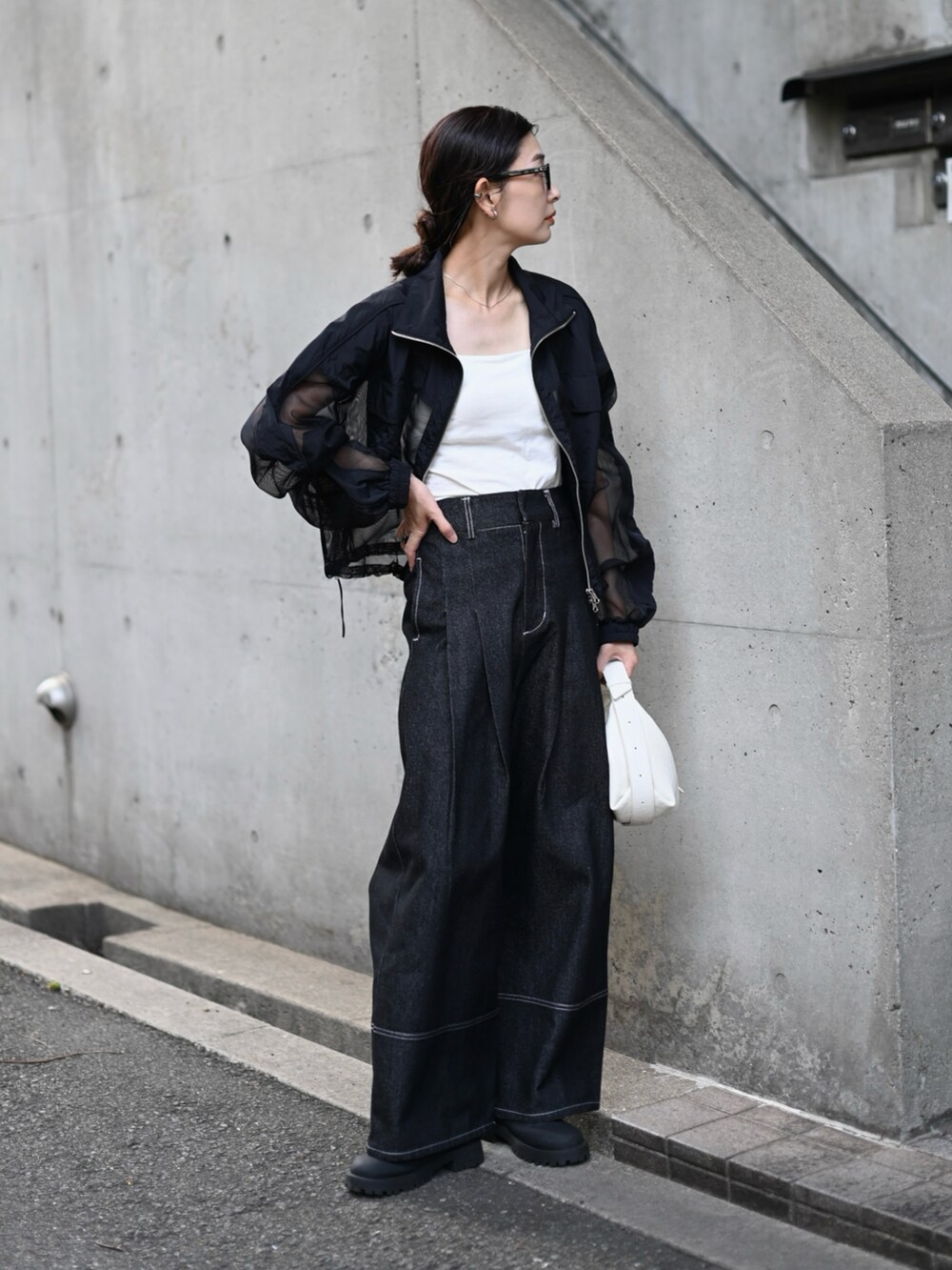 ブラック系のブルゾン、ブラック系のデニムパンツ、ホワイト系のショルダーバッグを着用したレディースの秋コーディネートの2枚目の写真